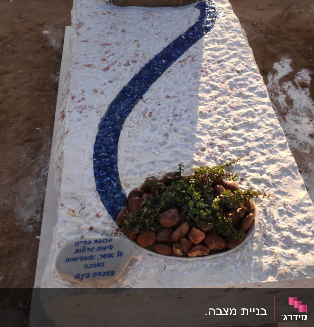 מצבה עם כיתוב בעברית, קישוטים ואבנים קטנות